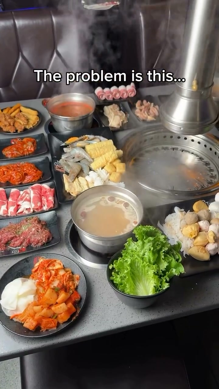 A KPOT Middletown table set with a hot pot of broth, a barbecue grill, sliced beef and pork, seafood, kimchi and lettuce